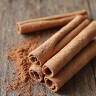 Unos rollos de canela y palos de canela en rama sobre una superficie rústica.